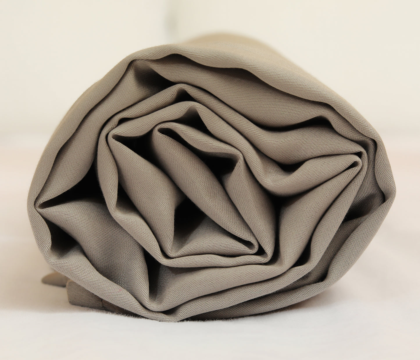 Dark grey fitted sheet neatly folded and rolled for display