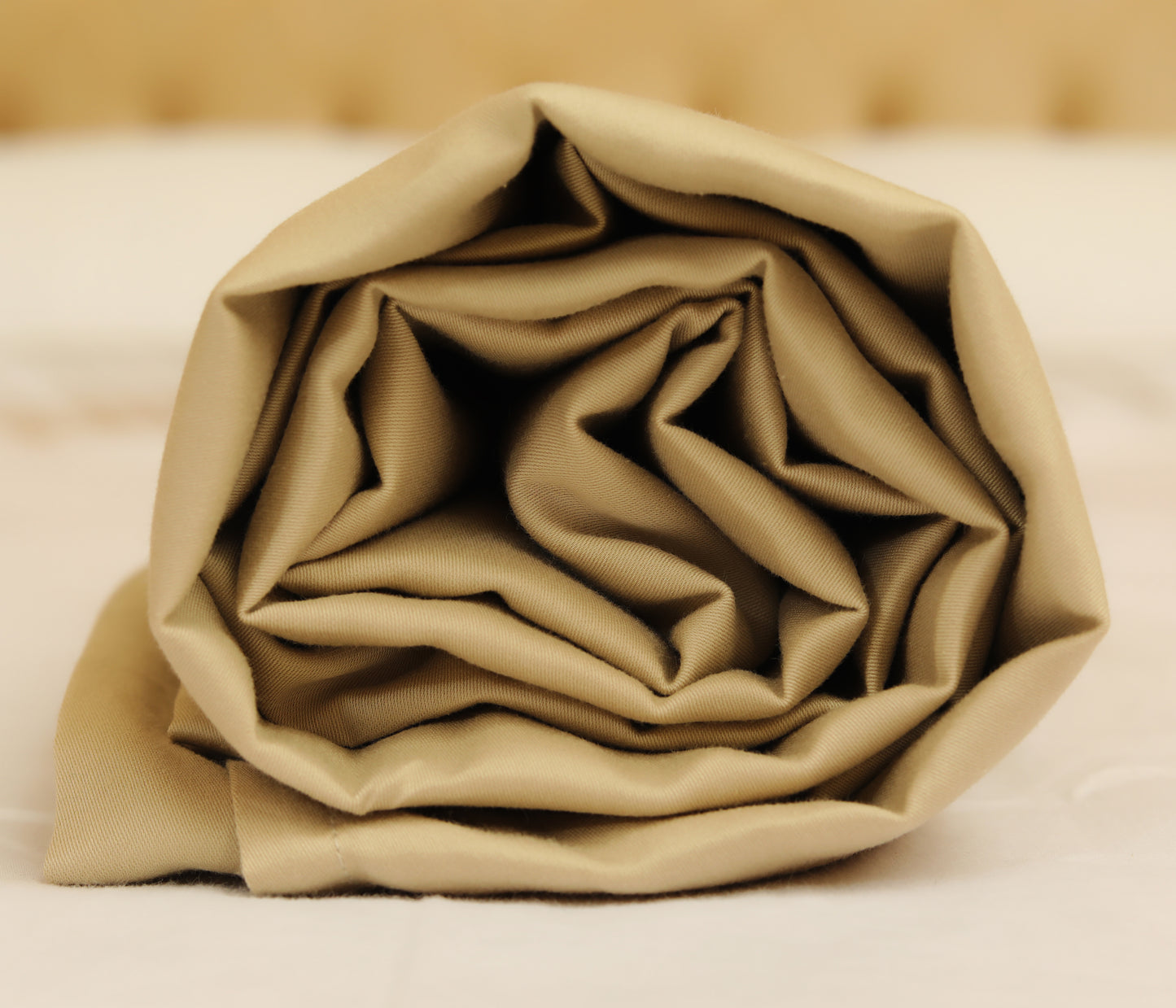 Greige cream fitted sheet neatly folded and rolled for display