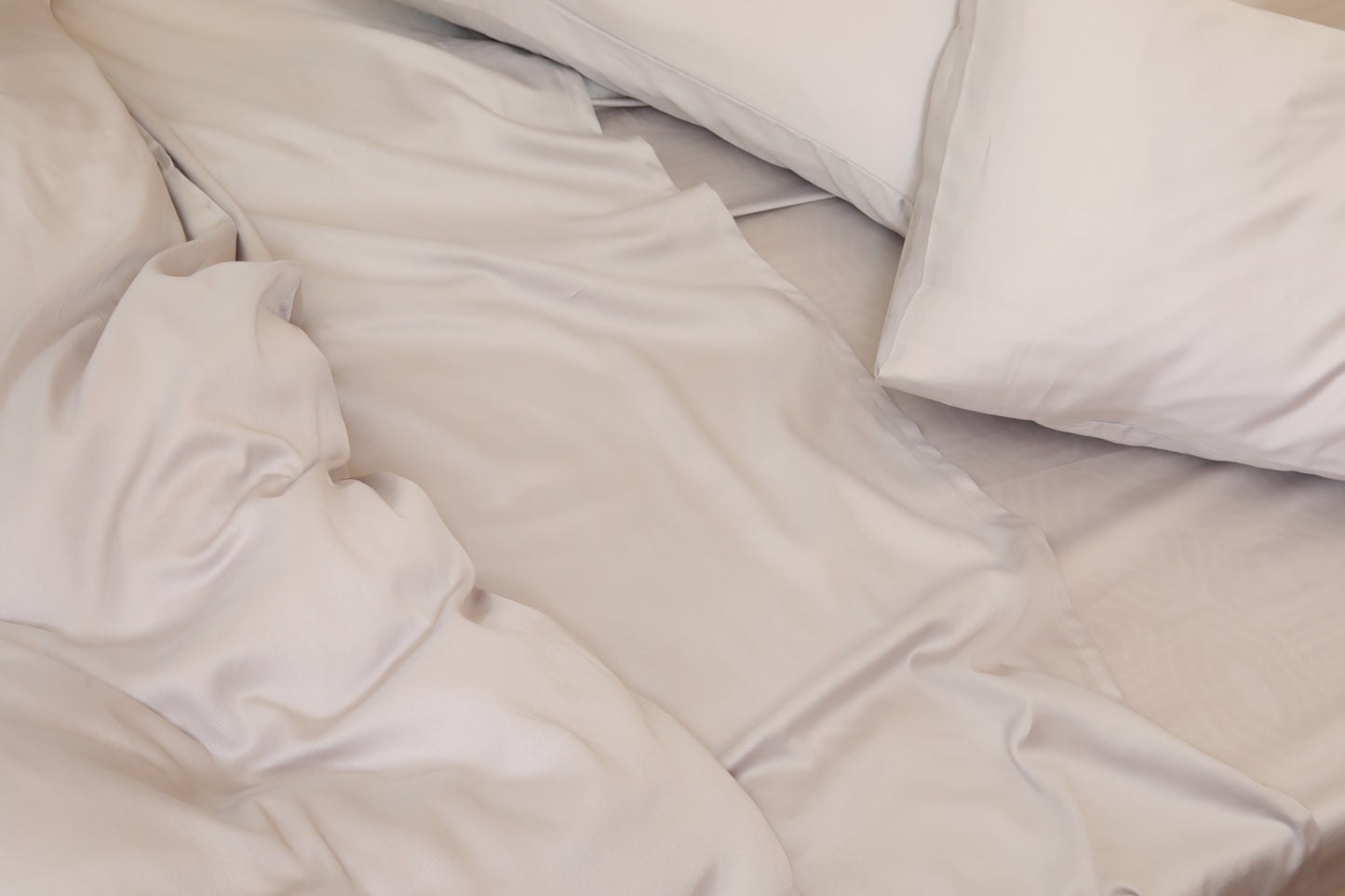 Soft light grey bed sheet set with pillows neatly arranged