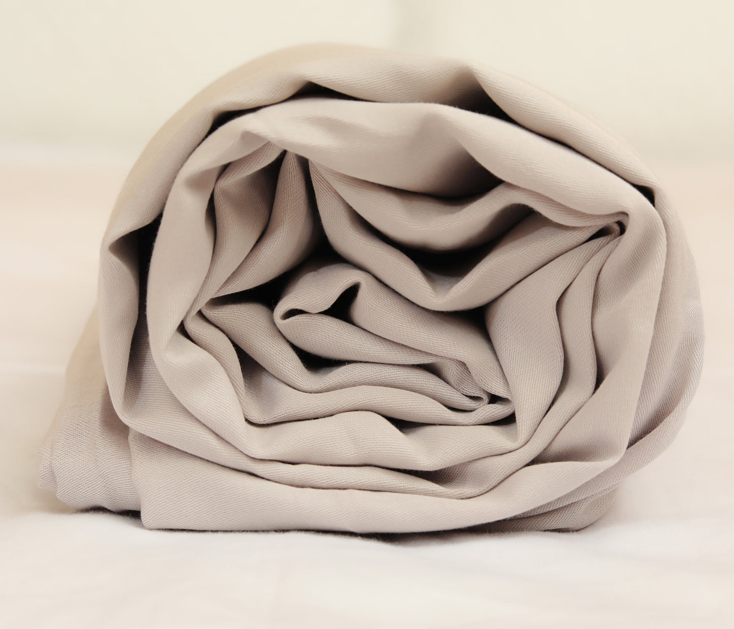 Light grey fitted sheet neatly folded and rolled for display