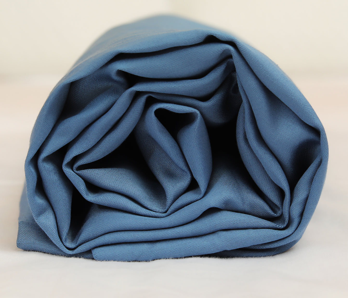 Midnight blue fitted sheet neatly folded and rolled for display