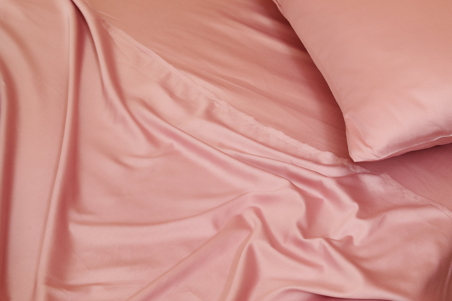 Soft pink bed sheets set with fabric folds close-up