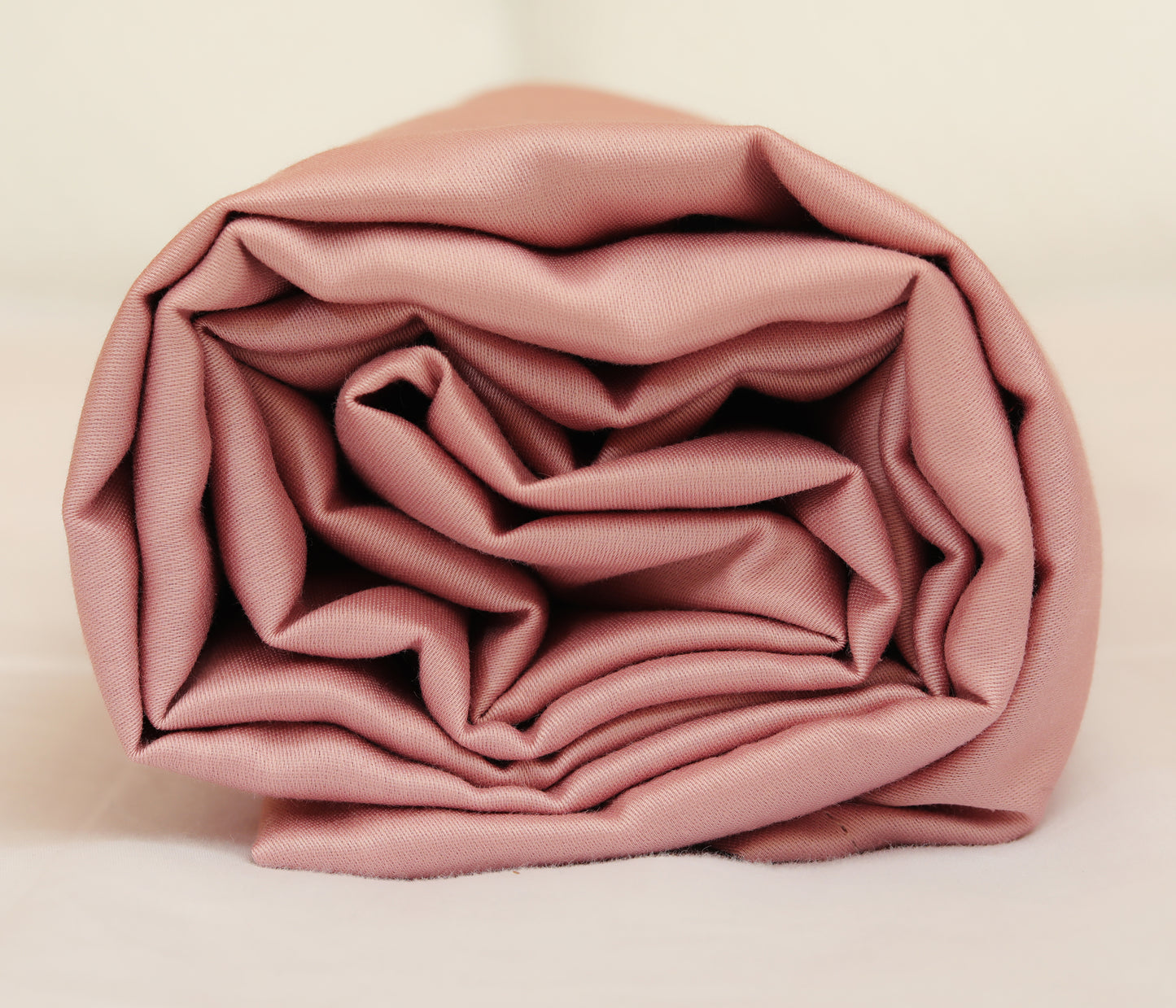 Pink fitted sheet neatly folded and rolled for display