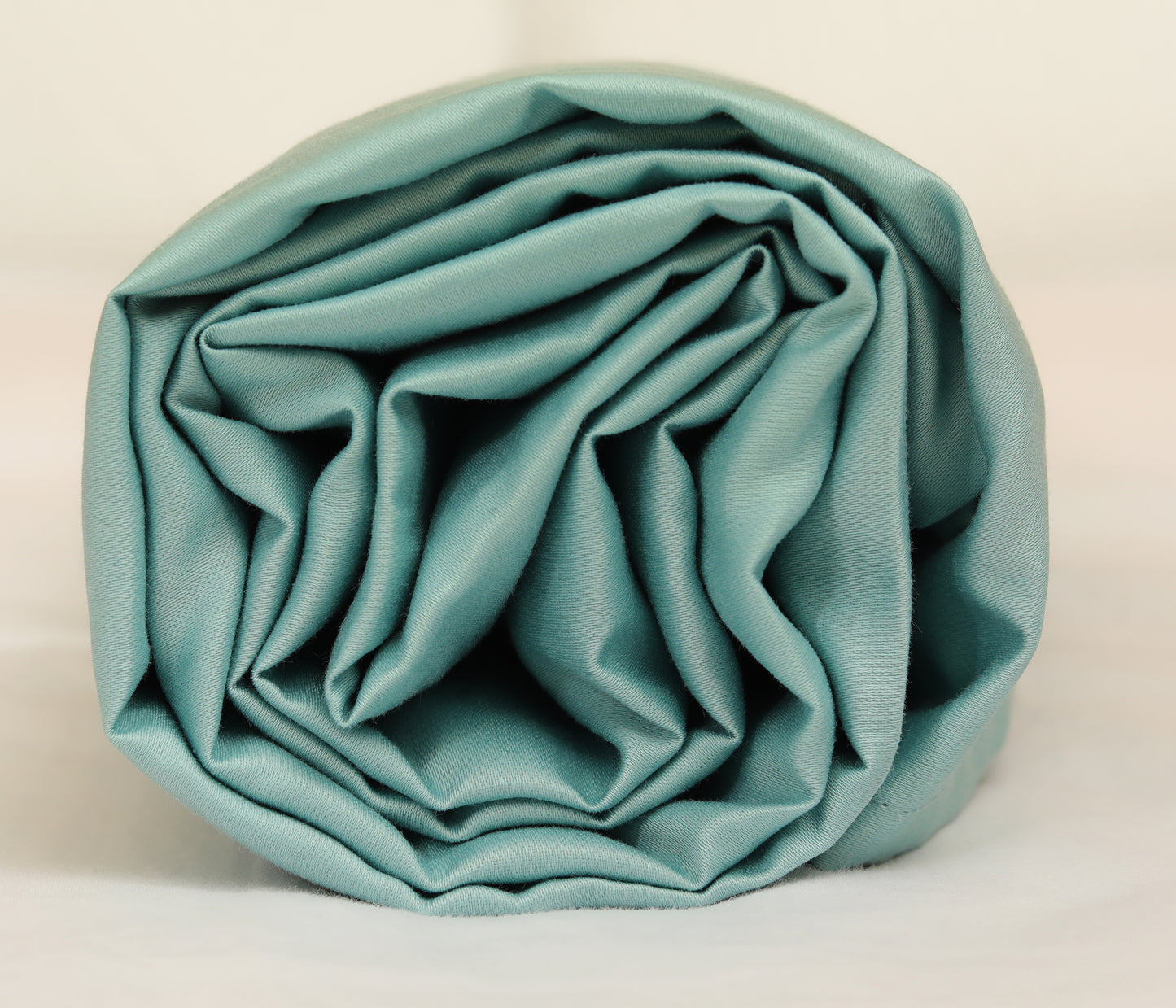 Sky blue fitted sheet neatly folded and rolled for display