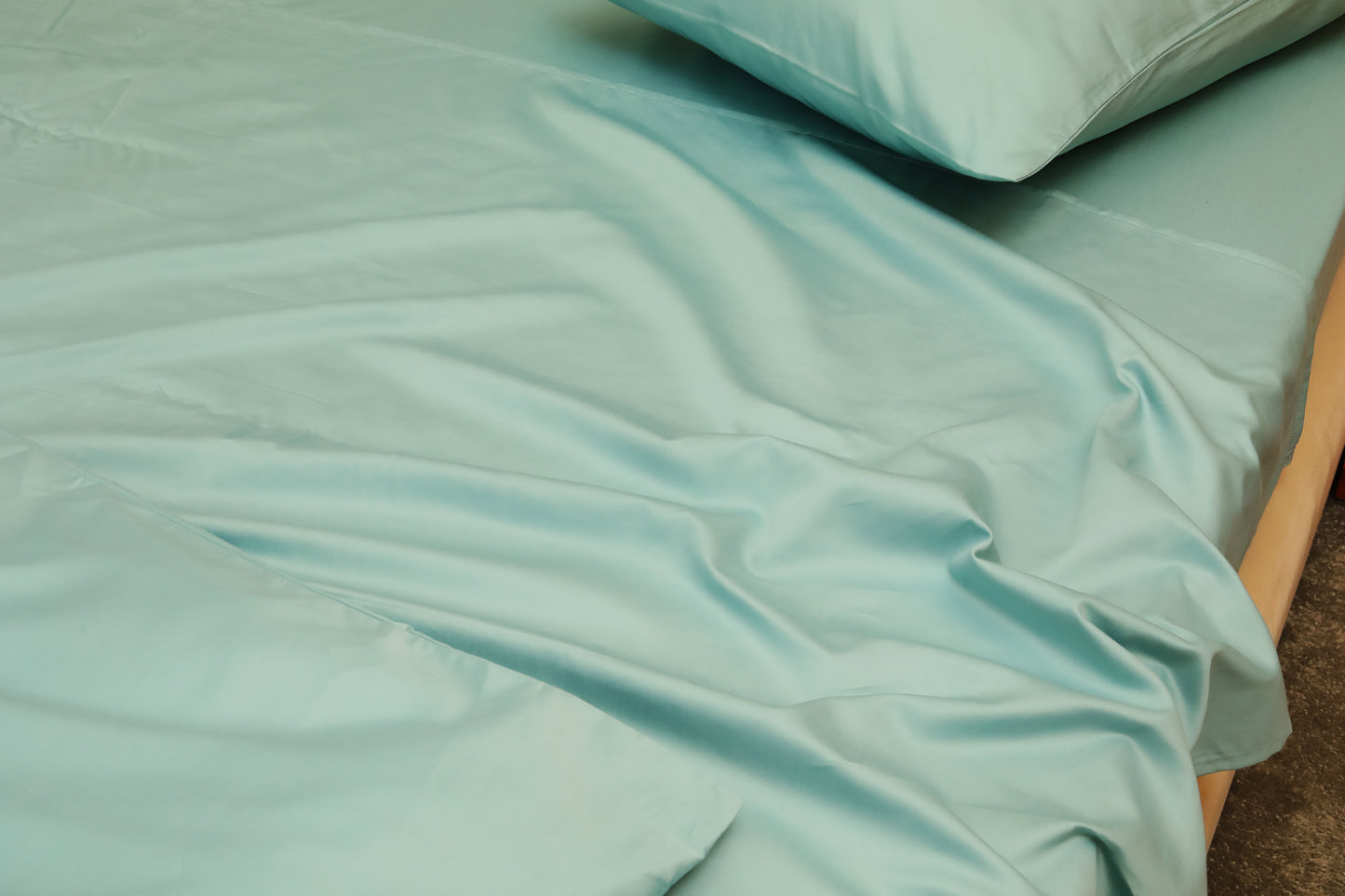 Sky blue fitted sheet with matching pillow on beige bed