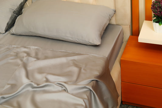 Dark grey fitted sheet with matching pillow on beige bed