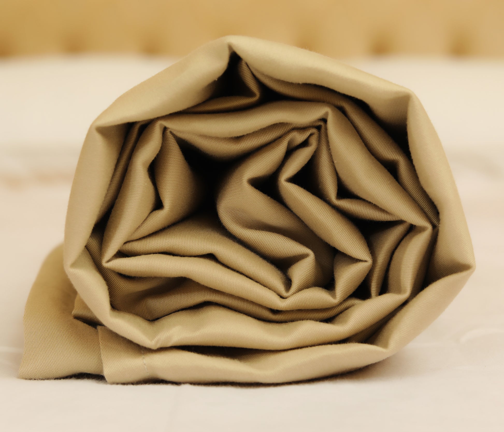 Greige cream bed sheets set neatly rolled for packaging
