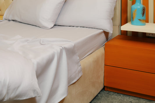 Light grey fitted sheet with matching pillow on beige bed