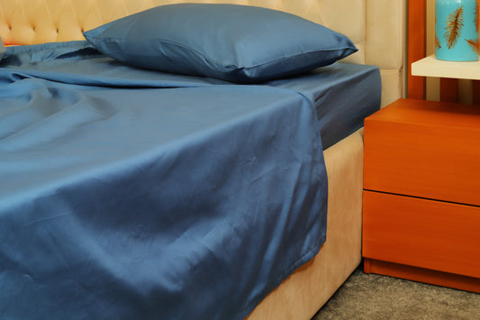 Midnight blue fitted sheet with matching pillow on a beige bed