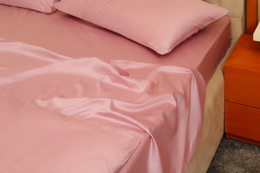 Pink fitted sheet with matching pillow on a beige bed