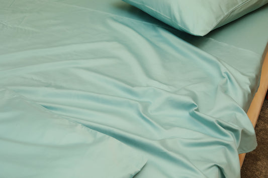 Sky blue fitted sheet with matching pillow on beige bed